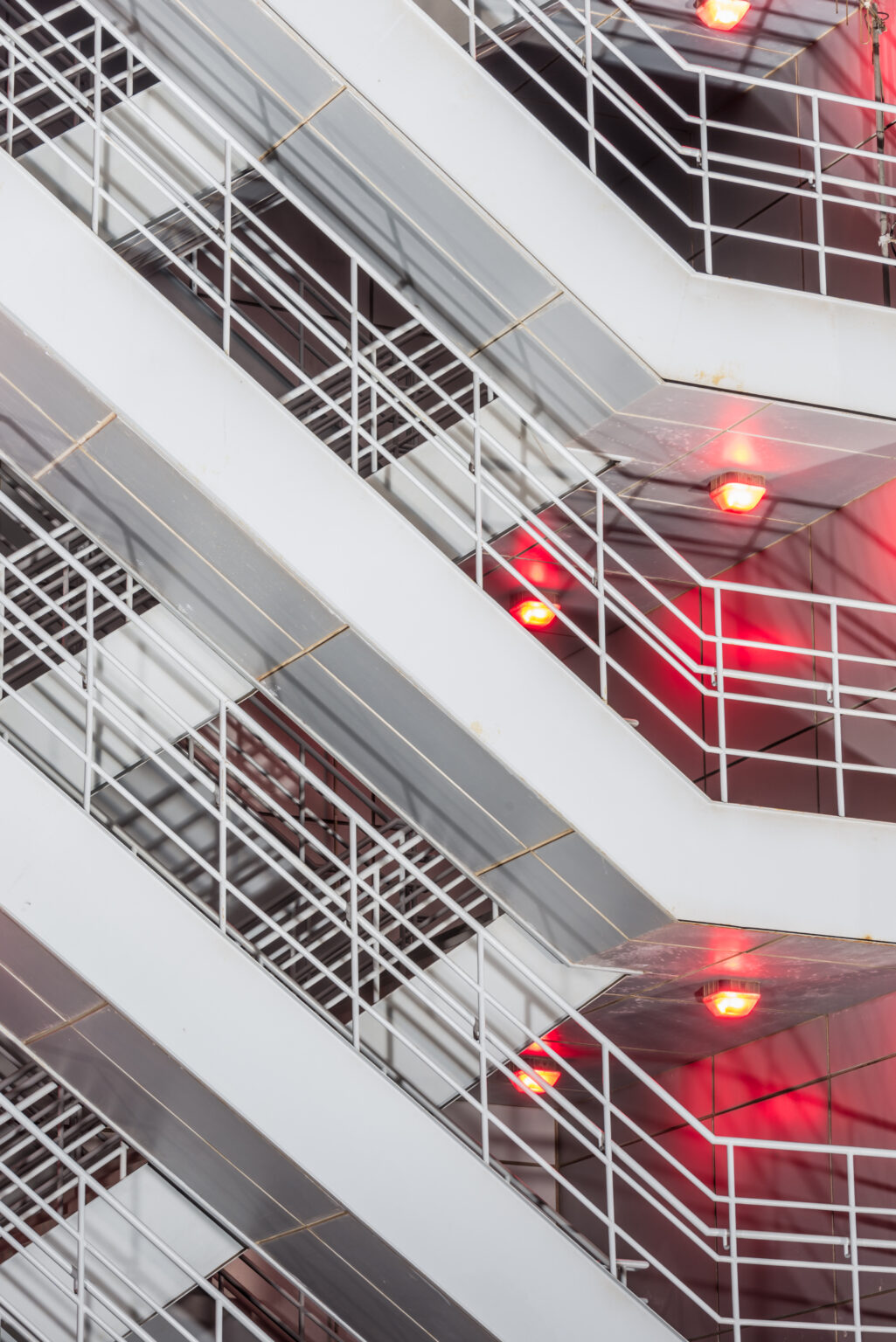 Treppenhaus mit modernen Metallgeländern und aktivierter roter Notbeleuchtung als Teil eines Brandmeldesystems